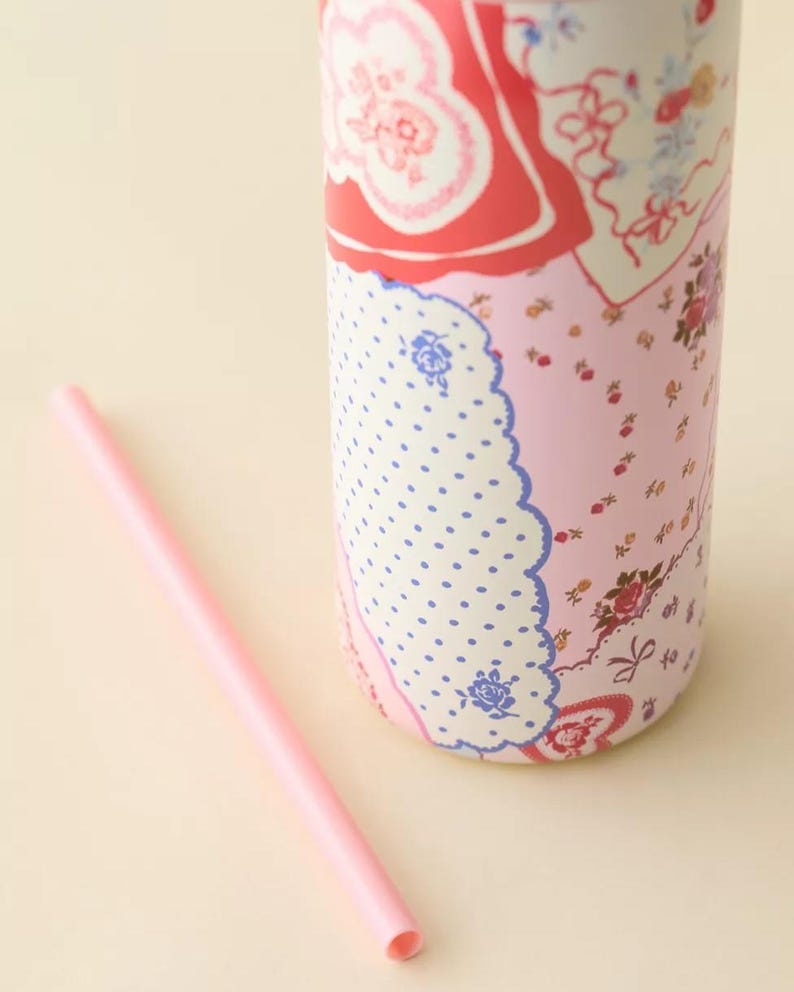 May include: A pink insulated tumbler with a floral and polka dot pattern, and a matching pink straw. The tumbler features a mix of red, pink, and blue floral designs, and a white polka dot pattern.