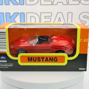 May include: A red Ford Mustang convertible model car in a box. The box is orange and black with the word "MUSTANG" in yellow. The model is 1:43 scale.