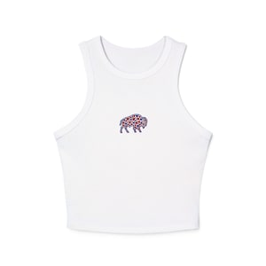 May include: White crop top with a small embroidered bison design. The bison is filled with red and blue star shapes. The top has a racerback style and is made of a soft, lightweight material.