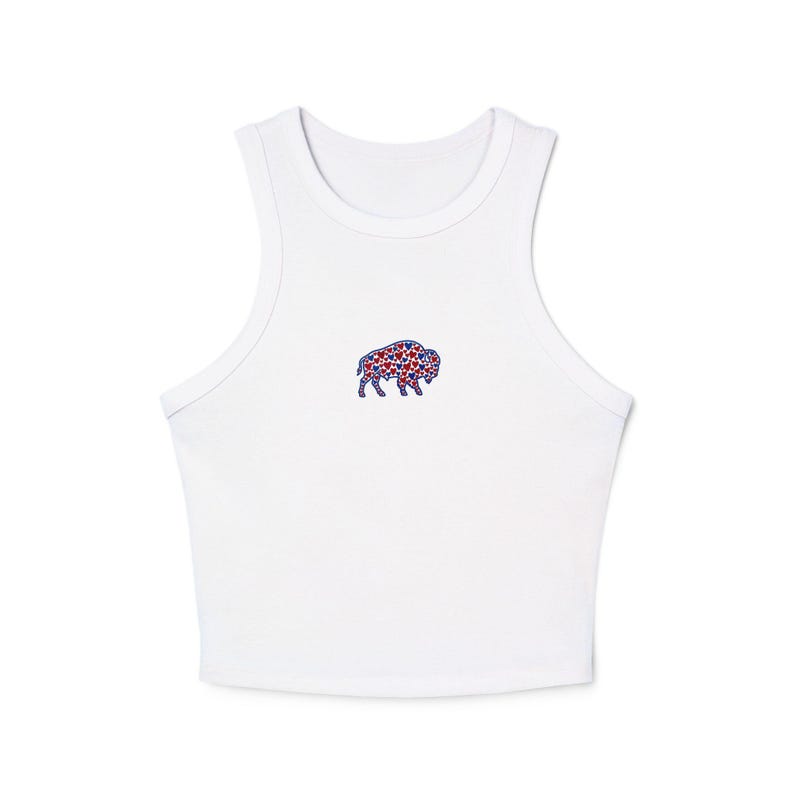 May include: White crop top with a small embroidered bison design. The bison is filled with red and blue star shapes. The top has a racerback style and is made of a soft, lightweight material.