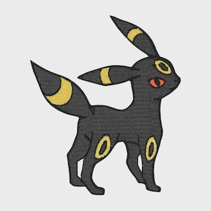 May include: An embroidered patch featuring a stylized black creature with pointed ears, a long tail, and bright yellow ring markings on its forehead, ears, tail, and legs. The creature has a single visible orange eye and a dark, textured thread finish.
