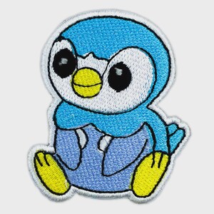 May include: An embroidered patch featuring a cartoon penguin character with bright blue plumage, a white face, large black eyes, and a yellow beak. The character has light blue accents on its body and yellow feet, all outlined in white thread.