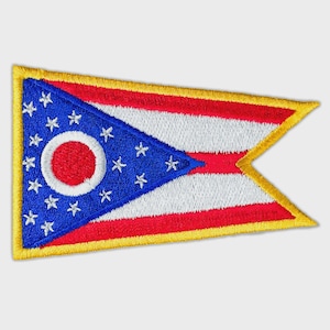 May include: A triangular embroidered patch featuring the Ohio state flag design. The patch has a blue triangle with a white circle and seventeen white stars, followed by red and white horizontal stripes, all bordered by a thick yellow edge.