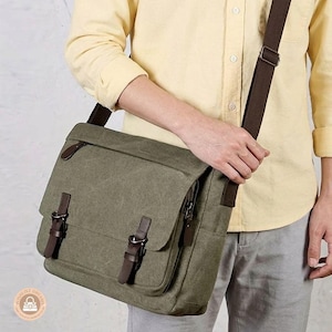 Peut inclure: Un sac messager en toile vert olive doté d'un rabat avec deux lanières en cuir marron foncé et des boucles métalliques. Le sac comprend une bandoulière réglable assortie en marron foncé et des fermetures éclair latérales pour le rangement.