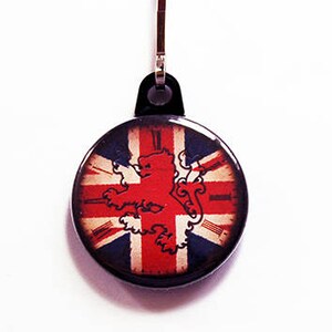 May include: A circular keychain featuring the Union Jack flag and a red lion emblem. The keychain has a black surround and a metal clasp. The background is plain white.