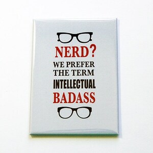 Może przedstawiać: Prostokątny biały magnes z napisem "NERD? WE PREFER THE TERM INTELLECTUAL BADASS" w kolorze czerwonym i czarnym. Projekt zawiera dwie pary czarnych okularów, jedną nad i jedną pod tekstem.