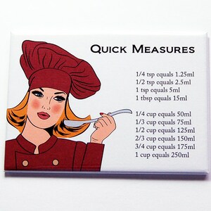 May include: A rectangular kitchen magnet featuring the text "QUICK MEASURES" and a retro illustration of a woman in a chef's hat. The magnet lists common kitchen measurements, including teaspoons, tablespoons, and cups, with their metric equivalents.