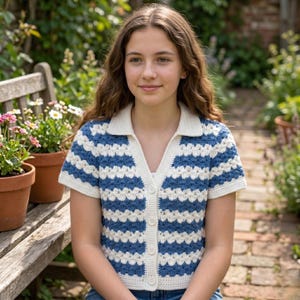 May include: A short-sleeved, button-down crochet top with a white collar and a blue and white striped pattern. The top is made of a soft, textured yarn and has a V-neckline. The top is worn by a person.