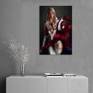 May include: A vertical wall art print featuring a blonde character in a white and red suit with a spider emblem, standing beside a red and blue costumed character with a spider emblem on the chest, both set against a dark, moody background.