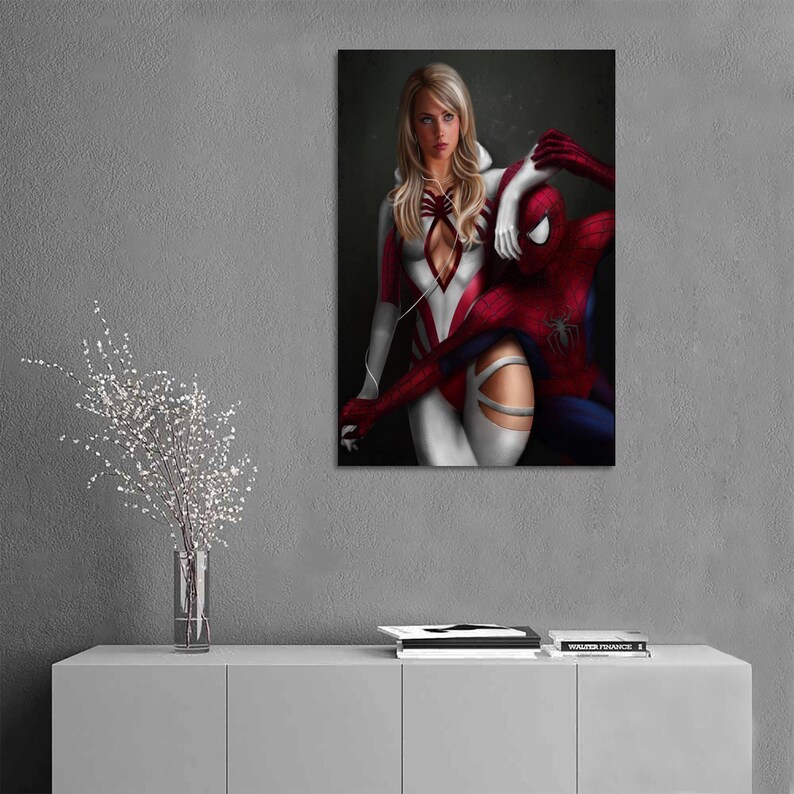May include: A vertical wall art print featuring a blonde character in a white and red suit with a spider emblem, standing beside a red and blue costumed character with a spider emblem on the chest, both set against a dark, moody background.