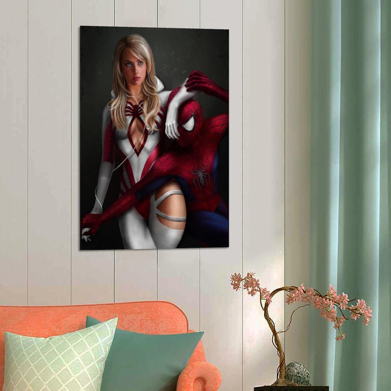 May include: A rectangular wall art print featuring a blonde woman in a white and red bodysuit with a spider emblem, standing beside a red and blue costumed superhero. The woman wears white headphones with a thin wire draped over her shoulders.