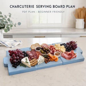 Könnte beinhalten: Ein hellblaues hölzernes Servierbrett für Wurstwaren mit dem Text CHARCUTERIE SERVING BOARD PLAN PDF PLAN - BEGINNER FRIENDLY. Das Brett ist mit Weintrauben, Brombeeren, Käseecken, Oliven, Salami, Crackern und getrockneten Aprikosen belegt.