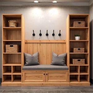 May include: A wooden entryway storage unit with built-in shelving, a bench with gray cushions, and storage cabinets. The unit features woven baskets, decorative hooks, and a small potted plant. The wood has a natural finish.