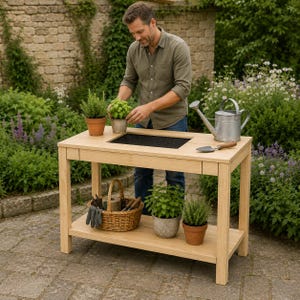 Könnte beinhalten: Eine Pflanzbank aus hellem Holz mit einer rechteckigen, schwarzen, eingelassenen Arbeitsfläche, einer unteren Ablage und einer Schublade. Auf der Bank stehen ein Weidenkorb mit Gartenwerkzeug, drei Topfpflanzen und eine Gießkanne aus Metall.
