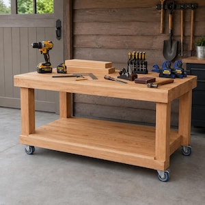May include: A rectangular wooden workbench with four caster wheels, featuring a thick top surface and a lower storage shelf. The workbench holds a yellow and black cordless drill, a tape measure, a metal square, wooden blocks, a set of screwdrivers, a hand plane, a sanding block, and two blue and black clamps.