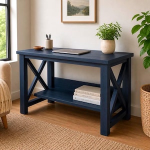 May include: A navy blue wooden desk with an X-shaped support on the sides. A laptop, books, and a potted plant sit on the desk. The desk is 48 inches long, 20 inches wide, and 30 inches high.