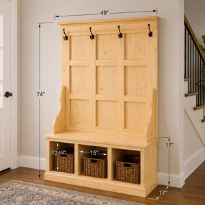 May include: A light wood hall tree with a bench, three storage cubbies, and a back panel with three black coat hooks. The hall tree is 74 inches high, 49 inches wide, and 17 inches deep. The storage cubbies each have a woven basket.