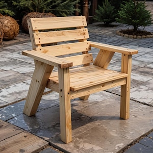Puede incluir: Una silla Adirondack de madera de color claro con respaldo y asiento de listones, y reposabrazos. La silla está construida con tornillos y juntas visibles, lo que sugiere un diseño artesanal. La silla está al aire libre en un patio de piedra.