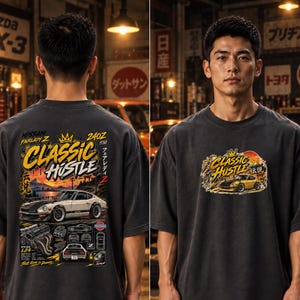 May include: A charcoal gray t-shirt featuring a graphic print of a Nissan Fairlady Z 240Z. The back displays a large illustration of the car, engine components, and the text "CLASSIC HUSTLE." The front features a smaller version of the same graphic.