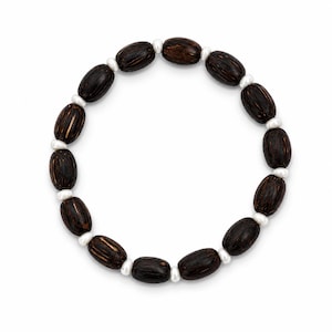Puede incluir: Una pulsera circular que presenta una alternancia de cuentas de madera ovaladas de color marrón oscuro y pequeñas cuentas redondas de color blanco. Las cuentas de madera muestran una textura veteada natural y un acabado suave.