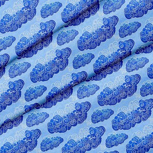 Könnte beinhalten: Ein hellblauer Stoff mit einem sich wiederholenden Muster aus dunkelblauen Wolken mit komplexen, wirbelnden weißen Liniendetails. Das Textil zeigt eine konsistente, dichte Anordnung dieser stilisierten Wolkenmotive auf der gesamten sichtbaren Fläche.