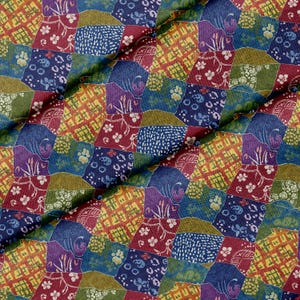 Op de afbeelding: Een stof met een patchworkontwerp van onregelmatige vierkanten in tinten donkerrood, olijfgroen, marineblauw en paars. Elk vierkant toont verschillende patronen, waaronder kleine witte bloemen, rasterlijnen, luipaardvlekken en abstracte wervelingen.