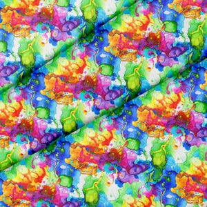 Könnte beinhalten: Ein Stoff mit einem lebendigen Aquarell-Druck, der überlappende Spritzer in leuchtendem Blau, Magenta, Limettengrün, Gelb und Orange zeigt. Das Muster besteht aus organischen, fließenden Formen und Spritzern, die ein buntes, abstraktes Design bilden.