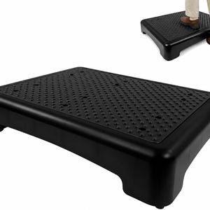 May include: A black rectangular step stool featuring a textured non-slip surface with a grid of small circular drainage holes. The platform is supported by four sturdy legs, providing a stable elevated surface for stepping or reaching items.