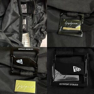 May include: Close-up of a black nylon jacket with multiple metal clasps and tags. The clasps feature the New Era logo and the text "US PATENT D729,619". The jacket has a minimalist design.