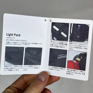 Peut inclure: Une &eacute;tiquette d'information produit rectangulaire blanche pour un sac &agrave; dos noir Light Pack. L'&eacute;tiquette affiche le texte Light Pack, volume 27L, et taille W300 x H460 x D230mm. Elle inclut six petites photos montrant les poches, une poche lat&eacute;rale, des fermetures &eacute;clair et une boucle pour casquette.