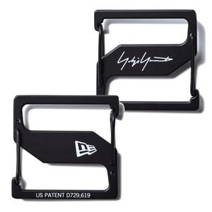 May include: Two black metal wallets with a rectangular frame design. One wallet features the white signature "Yohji Yamamoto", and the other displays the white "New Era" logo. The bottom wallet has the text "US PATENT D729,619".