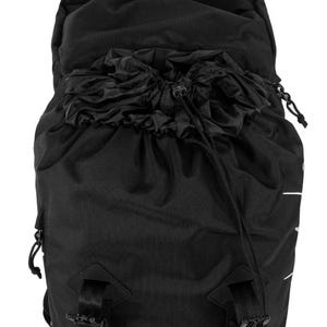 May include: Black backpack with a drawstring closure at the top. The backpack has adjustable straps and buckles. The material appears to be a durable, textured fabric. The design is minimalist and functional, suitable for various outdoor activities.