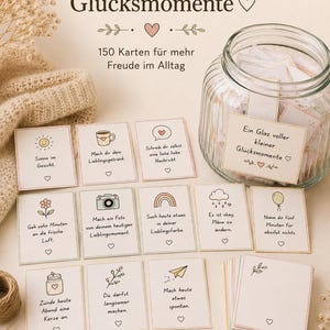 Puede incluir: Un frasco de vidrio lleno de 150 tarjetas peque&ntilde;as, cada una con una ilustraci&oacute;n &uacute;nica y texto en alem&aacute;n. Las tarjetas incluyen frases como 'Sonne im Gesicht' y 'Mach dir dein Lieblingsgetr&auml;nk'. Se incluye un bol&iacute;grafo negro y tarjetas en blanco.