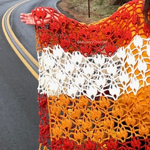 May include: A crochet shawl featuring a repeating tulip pattern in horizontal stripes of red, white, and orange yarn. The openwork design displays intricate floral motifs throughout the fabric. The text @MushyyCrochet is visible on the white section.