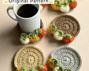 May include: Five circular crochet coasters in gray, tan, and brown, each featuring a row of small, stuffed pumpkins in orange, yellow, and white with green stems. A white ceramic mug filled with black coffee sits on one coaster. Text reads Original Pattern.