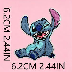 May include: An embroidered patch of the blue alien character Stitch, featuring a wide grin, large ears with pink inner details, and dark blue nose. The patch measures 6.2 cm by 6.2 cm, which is equivalent to 2.44 inches by 2.44 inches as indicated.