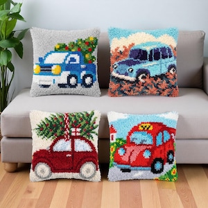 May include: Four square throw pillows featuring textured punch needle designs of vintage vehicles. The designs include a blue truck with a Christmas tree, a light blue car in a field, a red car carrying a tree, and a red taxi cab on a road.