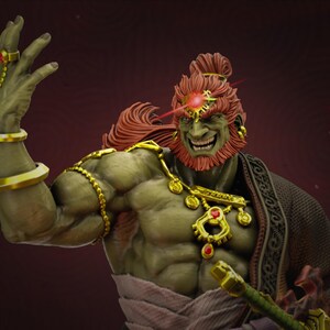 May include: A detailed figurine of a green-skinned character with red hair and beard, wearing gold jewelry and a dark robe. The figure has a menacing expression and is holding a sword. A red beam of light emanates from the character's forehead.