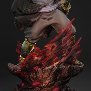 May include: A detailed figurine of a warrior figure, with green skin and ornate gold accents. The figure is posed above a base of fiery red and brown elements, holding a golden sword. The warrior is dressed in brown and white clothing with decorative patterns.