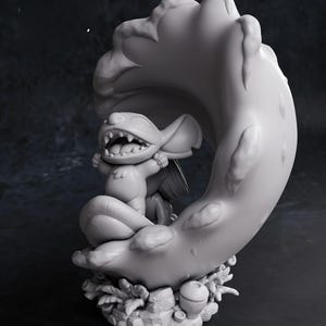 May include: A gray figurine of a cartoon character with large ears and a wide grin, seated on a crescent moon-shaped structure. The base features foliage and an acorn. The text "CHIBI TURNTABLE" is at the bottom.