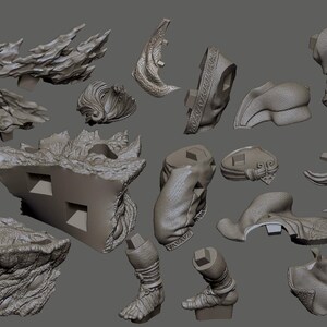 May include: A collection of gray 3D-printed model parts, including architectural elements, organic shapes, and stylized figures. The pieces vary in size and detail, with rough textures and intricate designs. The objects are arranged against a neutral gray background.