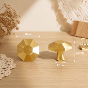 May include: Two gold-colored metal cabinet knobs with an octagonal faceted top. One knob is shown from the front, and the other is shown from the side. Dimensions are marked as 30mm in diameter, 25mm in height, and a 12mm base diameter.