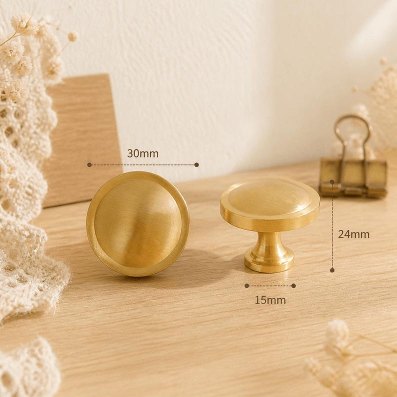 May include: Two round, brushed gold-tone metal cabinet knobs. One knob is shown from the top, and the other is shown from the side. The diameter is 30mm, the height is 24mm, and the base diameter is 15mm as indicated by the text labels.