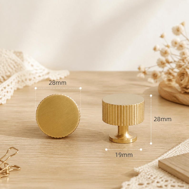 May include: Two circular brass cabinet knobs with a ribbed side texture. One knob is shown from the top, and the other is shown from the side. The knobs have a diameter of 28mm, a height of 28mm, and a base diameter of 19mm as indicated by labels.