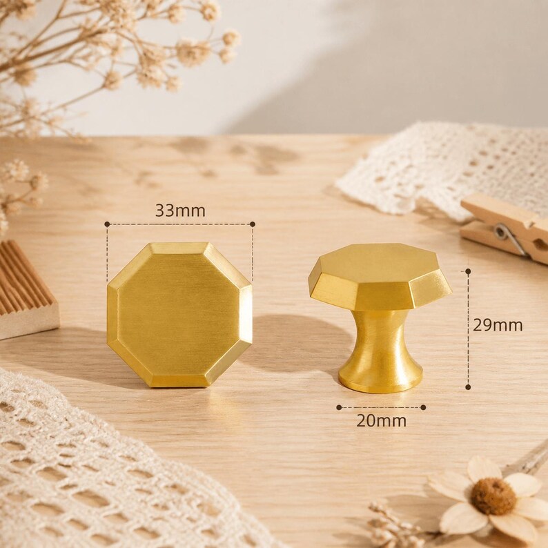 May include: Two gold-colored octagonal cabinet knobs with a brushed finish. One knob is shown from the front, and the other is shown from the side. Technical lines indicate a width of 33mm, a height of 29mm, and a base diameter of 20mm.