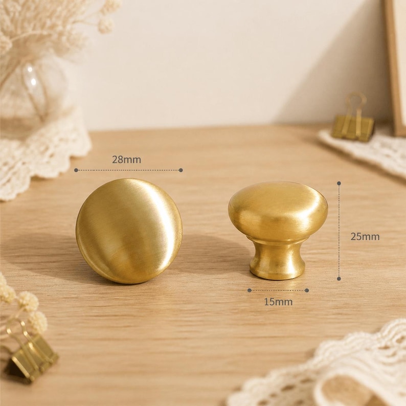 May include: Two round, brushed gold-tone metal cabinet knobs. One knob is shown from the top, and the other is shown from the side. Technical labels indicate a 28mm diameter, a 25mm height, and a 15mm base diameter for the hardware pieces.