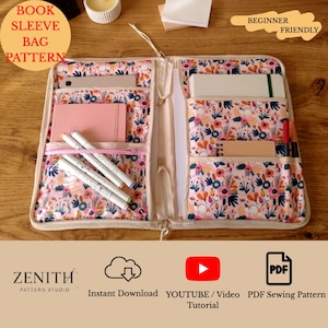 Könnte beinhalten: Offene Bucheinschlagtasche mit einem floralen Muster in Rosa, Blau und Weiß. Die Tasche hat mehrere Taschen und einen Reißverschluss. Der Text "BOOK SLEEVE BAG PATTERN" ist sichtbar. Die Worte "BEGINNER FRIENDLY" sind ebenfalls sichtbar.
