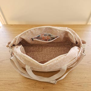 Inside view of the multi pocket baby bag showing organized diapers, baby bottles, clothes, and neat inner compartments.
