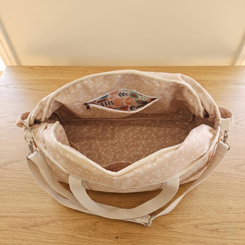 Inside view of the multi pocket baby bag showing organized diapers, baby bottles, clothes, and neat inner compartments.