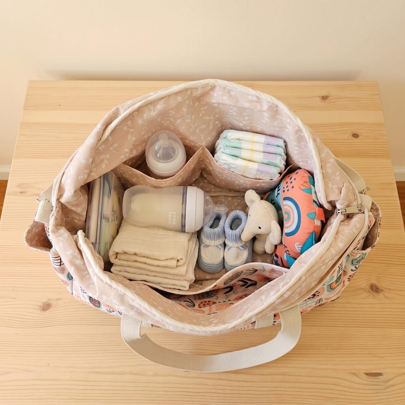 Inside view of the multi pocket baby bag showing organized diapers, baby bottles, clothes, and neat inner compartments.